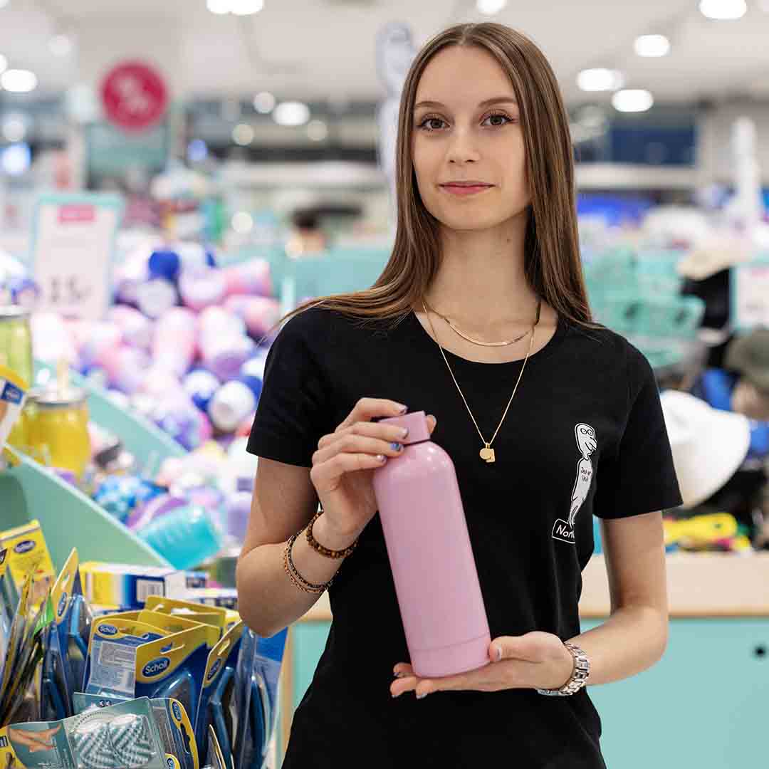 Medarbejder fra Normal på Frederiksberg, står med lyserød drikkedunk i hånden.